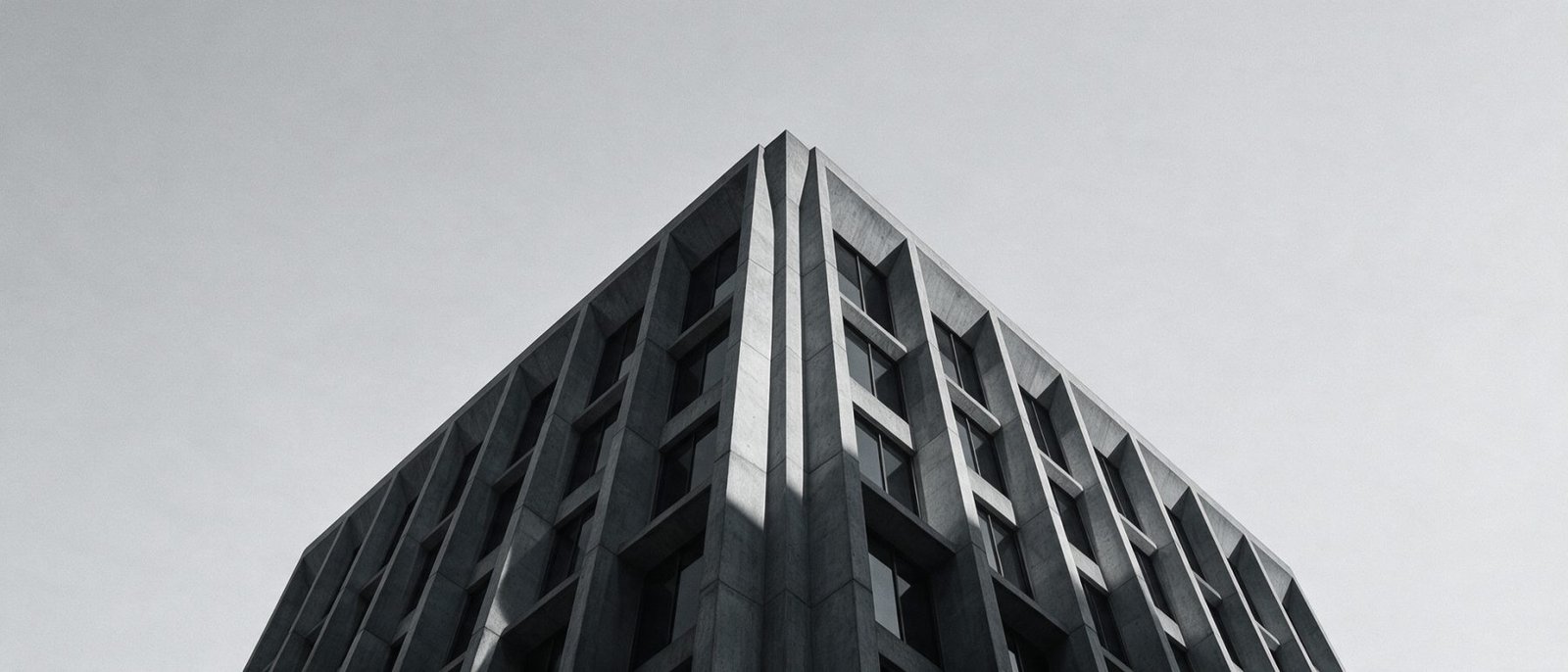 Low-angle view of a brutalist concrete tower against an overcast sky