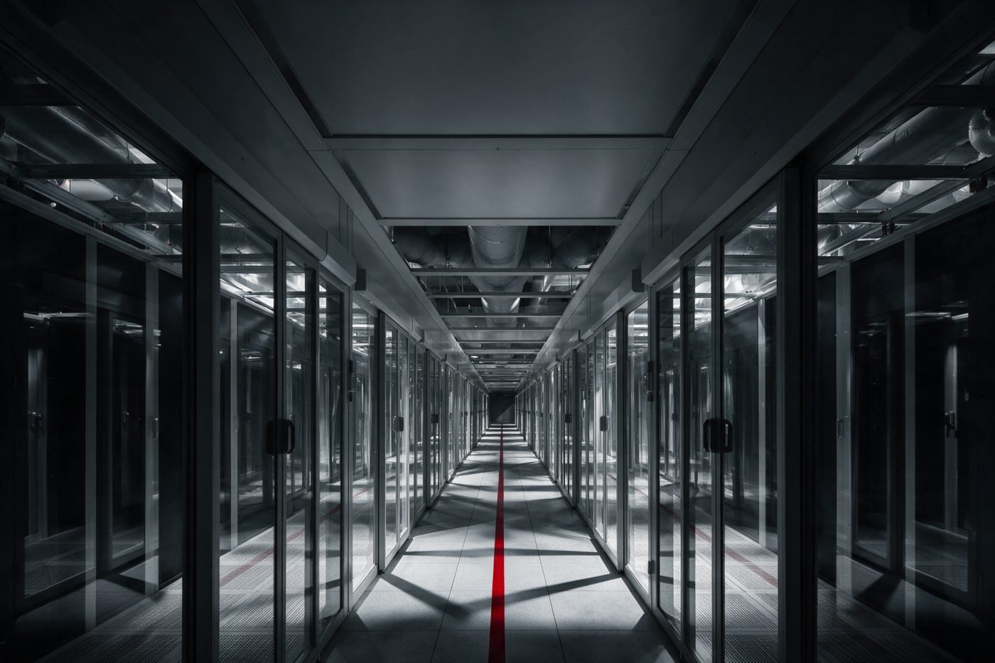 Hot-aisle containment corridor with glass panels and insulated cooling ducts overhead, a red floor stripe marking the aisle
