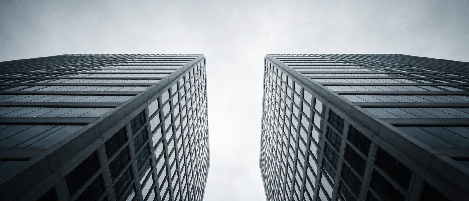 Contact GearTek - Looking up between two glass and concrete office towers toward a narrow slot of overcast sky