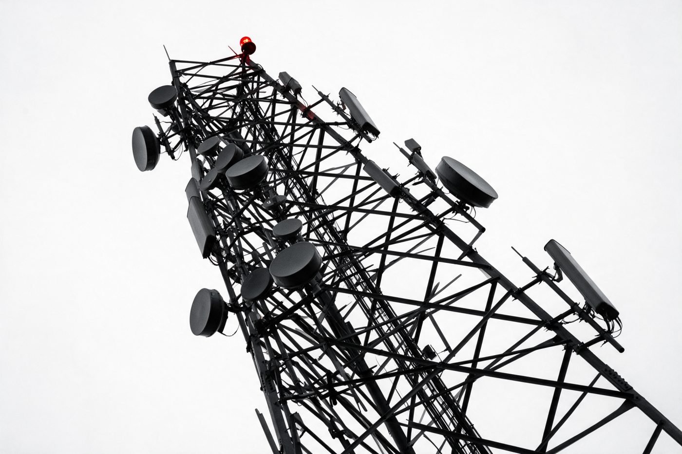 Lattice telecommunications tower with microwave dish arrays against a blank sky