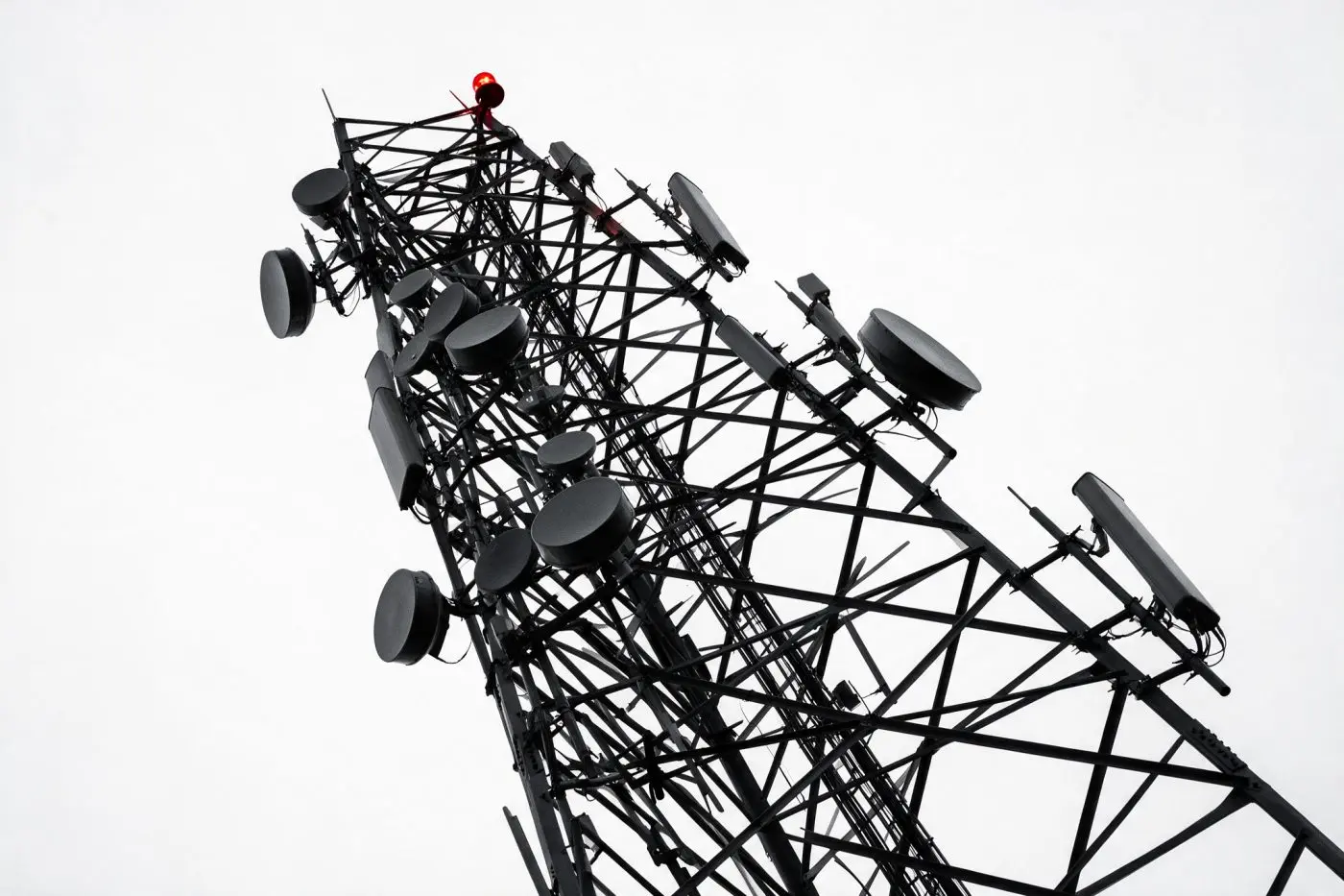 Lattice telecommunications tower with microwave dish arrays against a blank sky